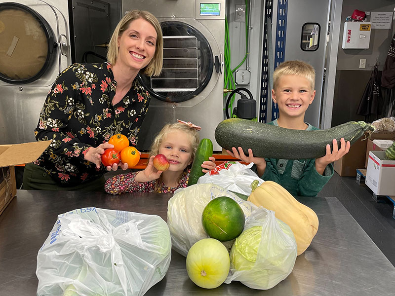 women and two children smiling with vegetables