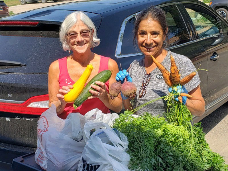 two women smiling and holding vegetables