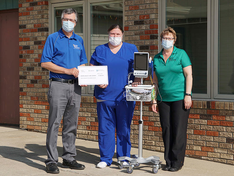 Three people standing with a temperature reader