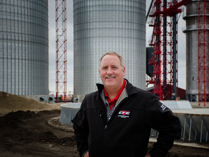 man standing in front of grain bins