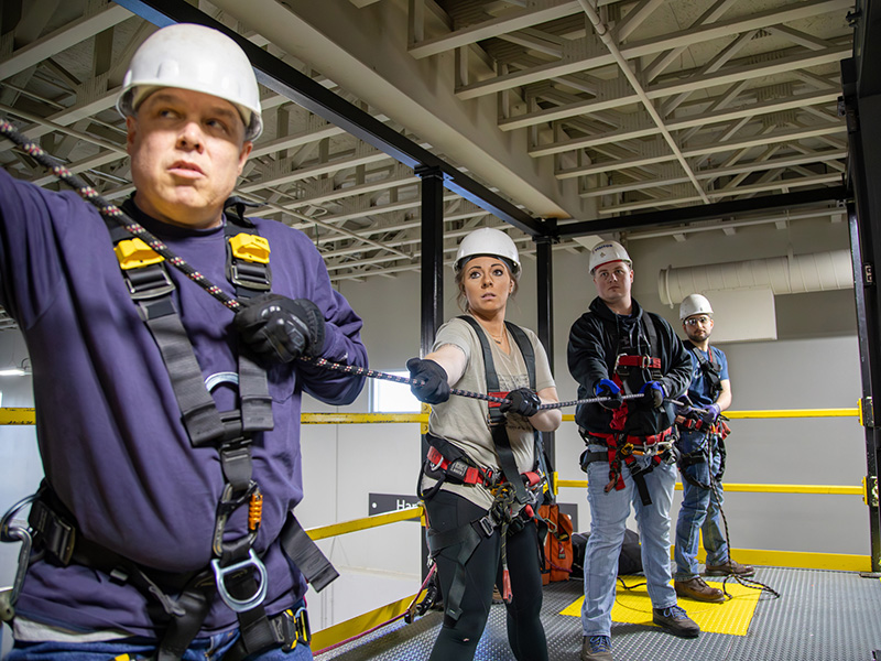 Four Dakota Gas employees hold a rope as they practice rope rescues.